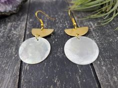 These lightweight earrings feature 25mm opalescent natural Filipino mirror shell discs dangling from 21mm x 10mm raw brass half-moon or semi-circle charms. The natural shell discs may have some yellow or pinkish inclusions. The ear wires are made of hypoallergenic gold-plated surgical steel, making these safe for sensitive ears.These earrings measure approximately 2 inches from the top of the ear wires to the bottom of the oval charm and are very lightweight, weighing just 0.1 ounce each.Domesti White Round Moon Phase Earrings, Seashell Earrings, Bronze Earrings, Gold Statement Earrings, Lightweight Earrings, Wooden Earrings, Shell Earrings, Brass Jewelry, Light Weight Earrings