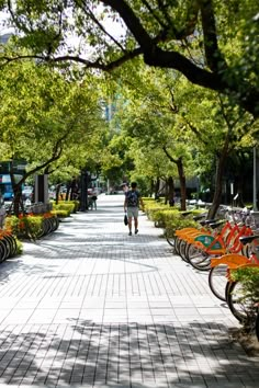 there is a man walking down the street with many bikes parked on either side of him