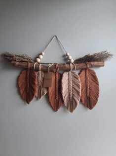 three feathers hang on a branch with a tag attached to the end, and some beads hanging from it