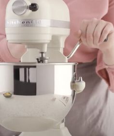 a woman is using a mixer to make something