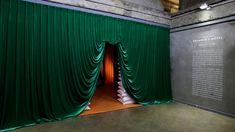 an open green curtain in front of a wall with writing on it that says voge