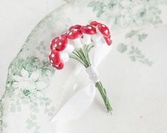 a red and white flower with polka dots on it sitting on a green leafy plate