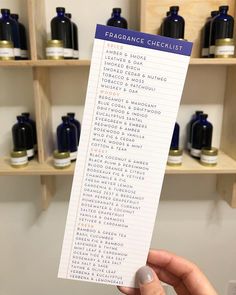 a person holding up a paper with some writing on it in front of shelves filled with bottles