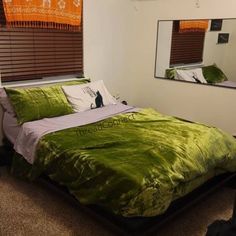 a bedroom with a green bed and mirror