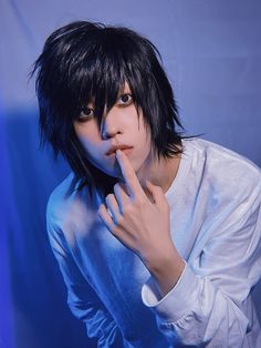 a young man with black hair posing for a photo in front of a blue background