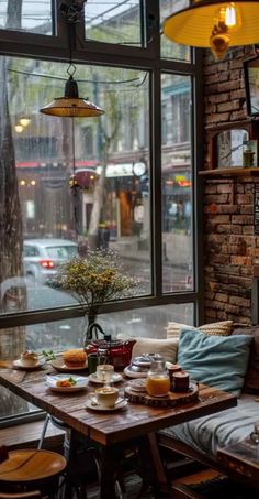 a table with food on it sitting in front of a window next to a brick wall