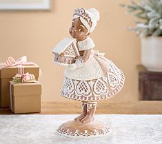 a little figurine that is sitting on a table next to a present box