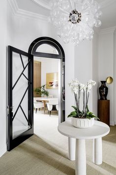 a white table with flowers on it in front of an open door to the living room