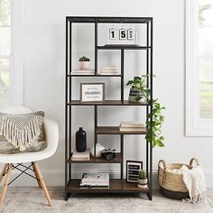 a shelf with books, plants and pictures on it in the corner of a room