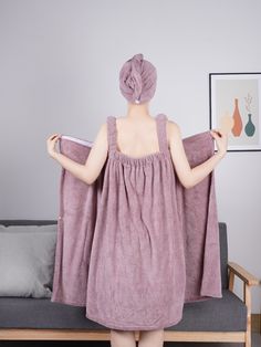 a woman standing in front of a couch holding a towel