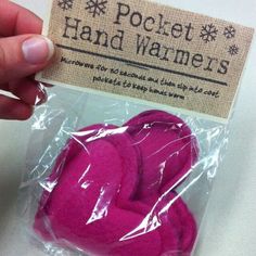 a person is holding up a pink heart shaped object in plastic wrapper on a white surface