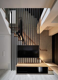 a tv sitting on top of a wooden shelf next to a stair case in a living room