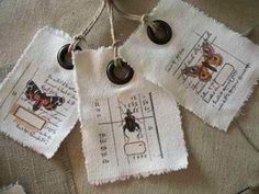 three pieces of fabric hanging from strings with buttons and tags attached to them on a table