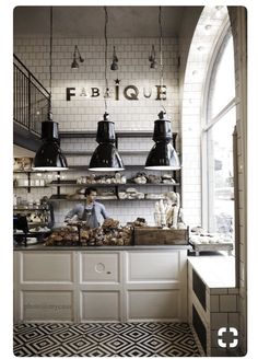 the interior of a restaurant with black and white tiles on the floor, counter tops, and hanging lights