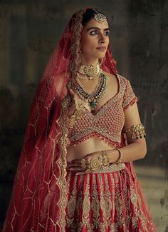 Featuring the Bridal Red Silk Embroidered Lehenga is a stunning creation of traditional artistry, tailored for brides seeking elegance on their special day. Crafted from luxurious raw silk, the richly detailed red lehenga is adorned with intricate tissue applique and dori work, brought to life by shimmering dabka beads, crystals, and sequins. Paired with a beautifully embroidered blouse with eye-catching red tassels along the waistline and sleeve edges, adding a playful yet sophisticated detail. The look is completed by a heavily embroidered net dupatta that drapes elegantly. This lehenga is a timeless, versatile piece designed to make any bride shine on her special day, exuding both elegance and sophistication. Composition : Lehenga, Blouse - Raw Silk and Dupatta - Soft Net Care: Dry Clea Dori Work, Red Lehenga, Embroidered Lehenga, Indian Wedding Wear, Lehenga Blouse, Net Dupatta, Red Silk, Shine On, Wedding Wear