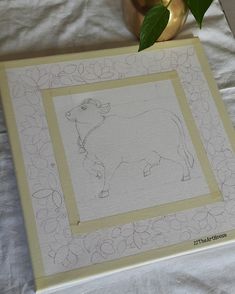 a drawing of a cow in a frame next to a vase