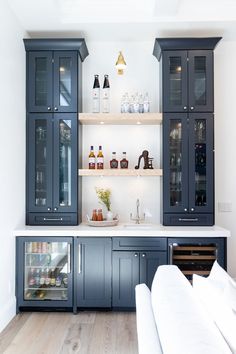 a kitchen with dark blue cabinets and white counter tops is pictured in this image, the shelves are filled with liquor bottles