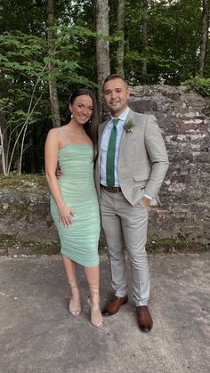 a man and woman standing next to each other in front of a tree filled forest