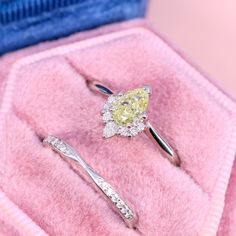 two diamond engagement rings sitting on top of a pink velvet box with the ring in it's holder