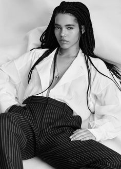 a black and white photo of a woman with dreadlocks sitting on a couch