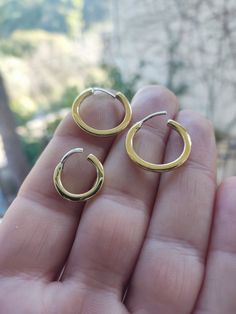 two small gold hoop earrings on someone's hand