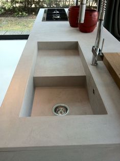 a sink in the middle of a counter top with a window behind it and plants on the other side