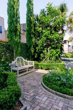 a wooden bench sitting in the middle of a garden next to a lush green hedge