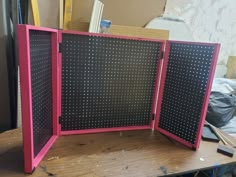 an open pink and black board sitting on top of a wooden table