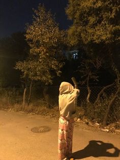 a skateboarder is standing on the street at night