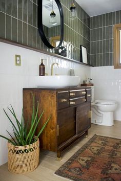 a white toilet sitting next to a wooden cabinet in a bathroom under a large mirror