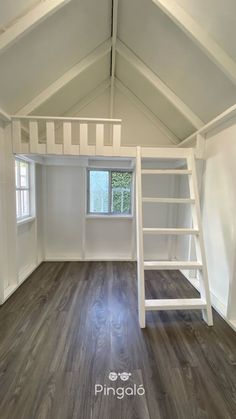 an empty room with white walls and wooden floors, ladders to the top floor