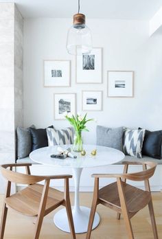 a white table with some chairs around it and pictures on the wall behind it,