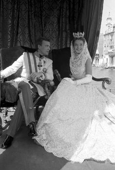 an old black and white photo of a man and woman in wedding attire sitting next to each other