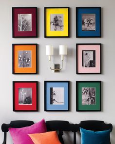 a black couch with colorful pillows and pictures on the wall