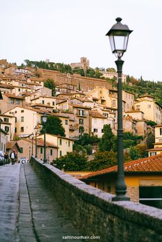 a street light sitting on the side of a stone wall next to a cityscape