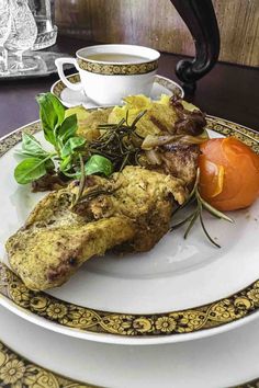 a white plate topped with meat and veggies next to a cup of coffee