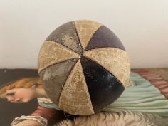 an old ball sitting on top of a table next to a painting with a woman's face