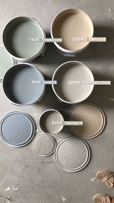 several different colors of paint sitting next to each other on top of a cement floor