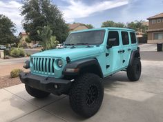 a light blue jeep parked in front of a house