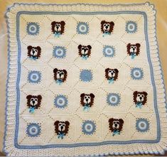 a white crocheted blanket with brown and blue bears on it's sides