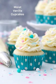 cupcakes with white frosting and sprinkles on a table next to a cake server