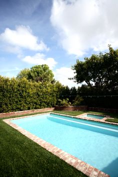 an empty swimming pool in the middle of a lush green yard with trees and bushes