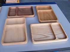 four wooden trays sitting on top of a table next to each other with different shapes and sizes