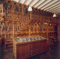 a room filled with lots of wooden shelves and drawers next to a stair case covered in clocks