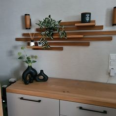 a wooden table topped with two vases next to a wall mounted shelf filled with plants