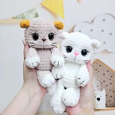 two small crocheted kittens are being held by someone's hands in front of a wall