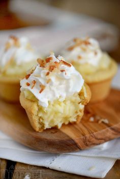 two cupcakes with white frosting and sprinkles on a wooden tray