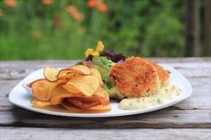 a white plate topped with potato chips and crab cakes