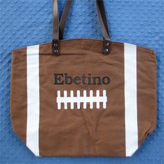 "This large, embroidered, personalized and monogrammed Football Tote Bag is a great way for a football mom or football girlfriend to carry all of her essentials to a game or anywhere to show her football pride. Football moms love to pack all their necessities in this bag and also display their team pride! This makes a great football gift for a team mom. The large, fully lined, cotton football bag measures 22\" x 17\" x 8\". It features a zippered pocket, 11\" leather drop handles. and a magnetic Brown Bag With Embroidered Logo For Everyday Use, Sporty Bags For Football Season, Personalized Brown Bags For Everyday Use, Personalized Sporty Bags For Sports Events, Personalized Bags For Everyday School Use, Sporty Personalized Bag For Sports Events, Customizable School Spirit Bag For Everyday, School Spirit Personalized Bags For Everyday Use, Customizable School Spirit Bags For Everyday Use