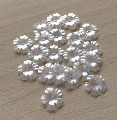 small white flowers on a wooden surface with one flower in the middle and two petals at the bottom